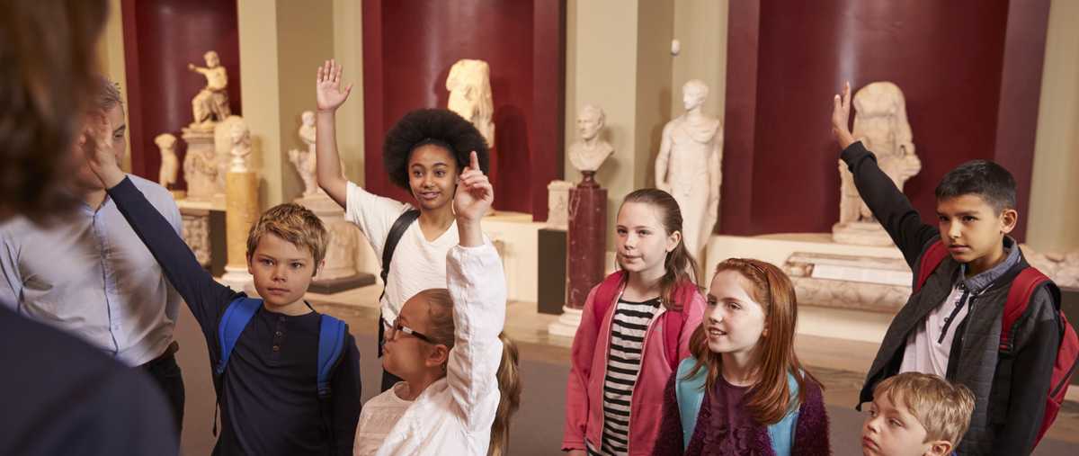 Pupils and teacher on a school field trip to a museum, with a guide.